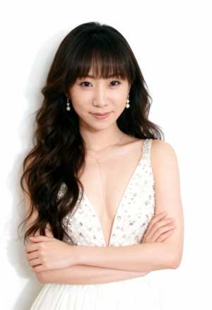 ウェーブのかかったダークブラウンの長い髪と前髪を持ち、大きく開いたネックラインと装飾...。