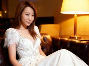 豪華なホテルのロビーで茶色の革張りのソファに座っている若いアジア人女性のポートレート。