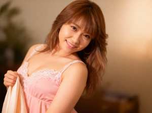 ウェーブのかかった茶色の長い髪を持つ若い女性が、ライトピンクの布地を手に持ちながらカ...。