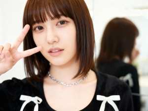 右手でピースサインをする若い女性をクローズアップカメラアングルから写実的に撮影したもの。