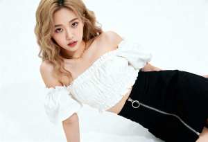 白いオフショルダーのトップスと前にジッパーが付いた黒いスカートを着て、無地の白い背景...。