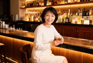 バーに座り、ウィスキーのグラスを持った中年のアジア人女性のポートレート。