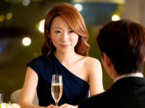 フォーマルな環境で男性の前でシャンパンを飲みながらテーブルに座る女性を、ポートレート...。