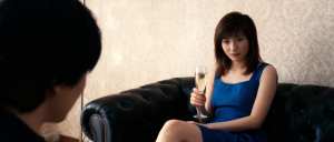 居心地の良いリビング ルームの黒い革張りのソファに座り、シャンパンのグラスを持ってい...。