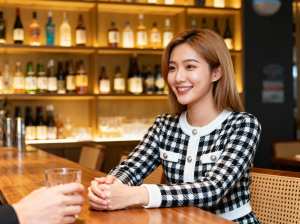 バーに座ってグラス一杯の水を前にカメラに向かって微笑む若い女性を、正面カメラのアング...。