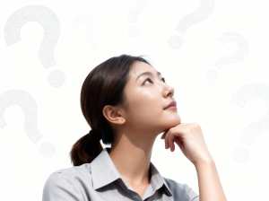 無地の白い背景に疑問符で囲まれた、思慮深い表情をしたアジア系の若い女性を横顔カメラの...。