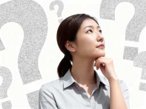 疑問符に囲まれ、思慮深い表情を浮かべたアジア系の若い女性を横顔カメラのアングルから写...。