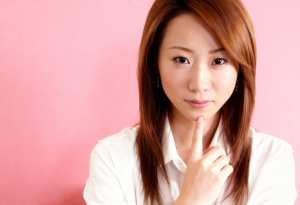 白い襟付きのシャツを着た、赤茶色の長くまっすぐな髪を持つ若いアジア人女性のポートレート。