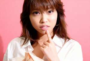 白い襟付きのシャツを着た、長く真っ直ぐな濃い茶色の髪と前髪を持つ若いアジア人女性の接写。