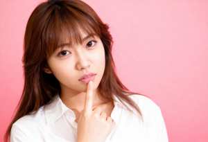 ピンク色の背景にポーズをとった、長くまっすぐな茶色の髪と白い肌を持つ若いアジア人女性...。