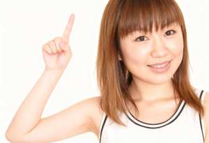 人差し指を上に向けた、陽気な表情の若いアジア人女性の接写。