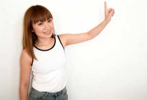 長くストレートな茶色の髪と前髪を持ち、白いタンクトップとブルー ジーンズを履いた若い...。