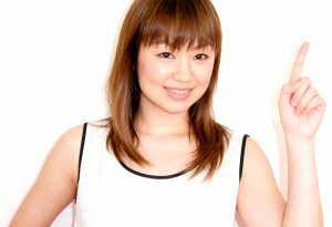 右手の人差し指を上に向け、明るい表情をした若い女性の写実的なポートレート。