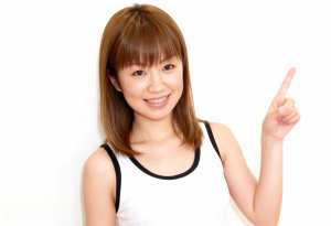 人差し指を上に向け、明るい表情をした若い女性。