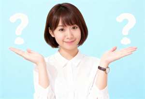 白い襟付きのシャツを着た、ショートボブのヘアカットをしたアジア系の若い女性が、頭の上...。