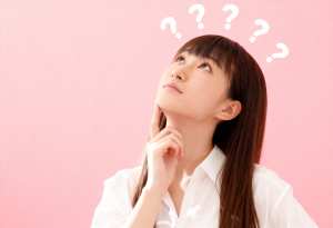 長い茶色の髪と頭上に浮かぶ疑問符に囲まれた思慮深い表情をした若い女性を横顔カメラのア...。