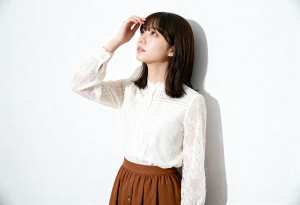 無地の白い壁に立っている若い女性。