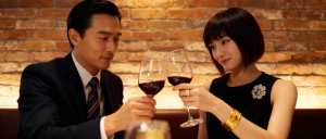 素朴なレンガの壁を背景に、薄暗いレストランのテーブルに座る男女を描いたロマンチックなシーン。