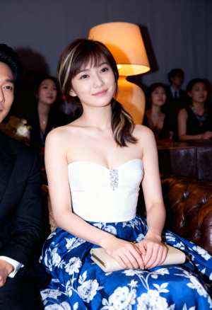 フォーマルなイベント会場で茶色の革張りのソファに座り、白いストラップレスのトップスと...。