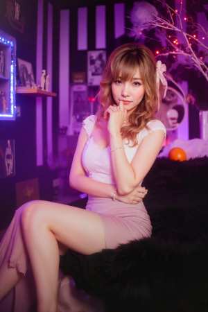 薄暗い部屋で毛皮で覆われた表面に座っている若い女性を横から撮影した写実的な写真。