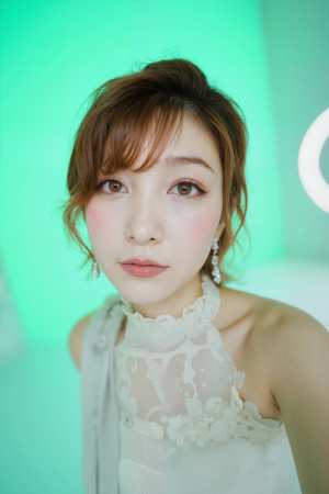 柔らかな光を当てた緑の背景に、薄手の白いドレスと揺れるイヤリングを身に着けた、柔らか...。