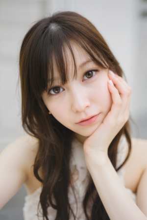 長くウェーブのかかった茶色の髪と白い肌を持つ若いアジア人女性が、あごを手に乗せてポー...。