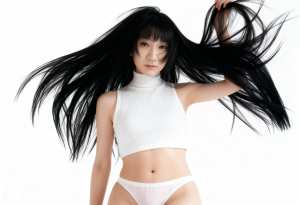 白いリブ編みのクロップトップとそれと一致するパンティーを着て、長い黒髪でポーズをとる...。