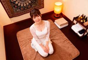 スパのような環境で茶色の敷物の上に座り、カメラに向かって微笑む若い女性を上から写実的...。