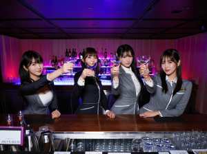 ビジネス服を着た 4 人の若い女性がバーカウンターの後ろに立ち、手にマティーニ グラ...。