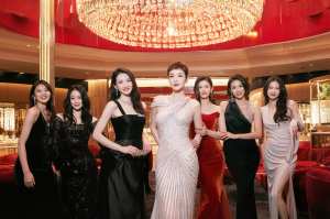 豪華なロビーに立ち、大きなシャンデリアの前で写真を撮る 7 人の女性のグループ。