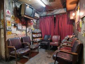 薄暗い部屋で、前景に茶色の革張りの椅子が並び、後ろに赤いカーテンがあり、素朴でビンテ...。