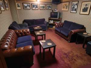 ヴィンテージ感あふれる薄暗いお部屋に、革張りのソファや椅子、テレビなどの家具を取り揃...。