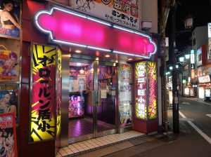 夜の日本の街のネオンが輝く店先を横から撮影した写真。
