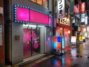 夜の日本の都市のネオンに照らされた街路シーンを写実的に描写したもので、ローアングルか...。