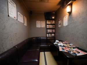 薄暗く、居心地の良い雰囲気のお部屋で、コーナーブースと新聞を敷いたテーブルが特徴です。