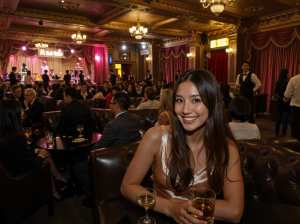 高級レストランのテーブルに座り、カメラに向かって微笑む女性。