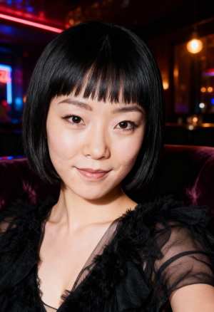 短い黒いボブのヘアカットと前髪を持ち、カメラに向かって直接微笑む若い女性のポートレート。