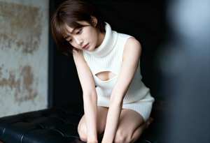 ミニマルなインテリアの中で黒い革張りのソファに座り、カットアウトのある白いノースリー...。