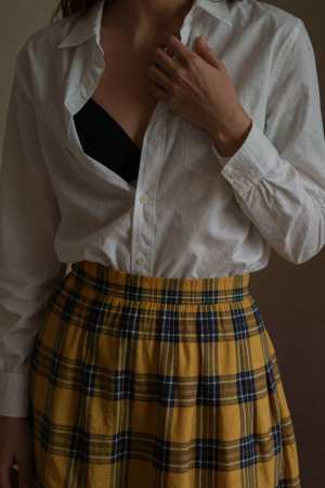 白いボタンダウン シャツと黄色のチェック柄のスカートを着た女性を、ローアングルの視点...。