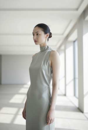 大きな窓のある空の部屋に立つ、ライトグレーのシルクドレスを着た若い女性を横顔カメラの...。