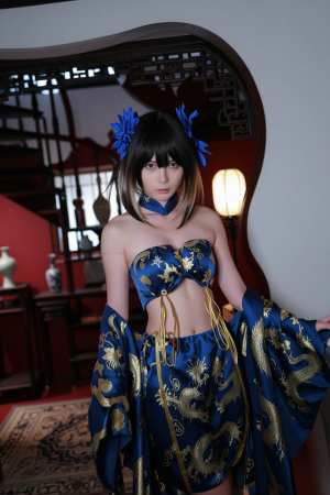 木製の階段と装飾的な鏡を背景にした薄暗い部屋に立つ、伝統的な東洋の衣装を着た若い女性...。