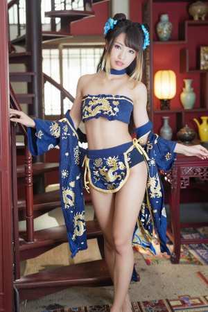 青と金の刺繍が施された衣装を着て、伝統的な東洋の雰囲気の中でポーズをとる若い女性を、...。