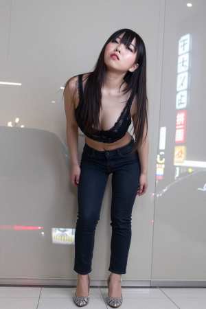 黒いレースのクロップトップとダークブルーのジーンズを着て、ガラスの壁に向かって自信を...。