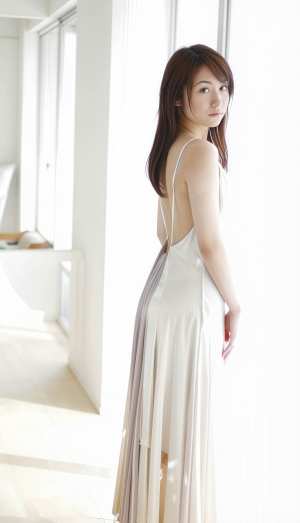 白いロングドレスを着てモダンなインテリア空間に立つ若い女性を横から見た写真のようにリ...。