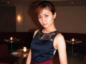 薄暗いレストランに立つ若い女性の写実的なポートレート。