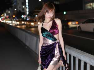 見事な紫と緑のベルベットのドレスを着て、夜の橋の上で自信を持ってポーズをとる若い女性...。