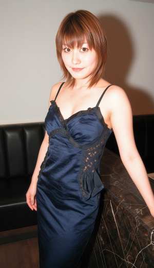 薄暗い部屋で黒い革張りのソファに向かって自信を持ってポーズをとる若い女性をポートレー...。