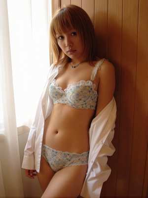 木製の壁を背景にランジェリー姿でポーズをとる若い女性を横から見た写実的な撮影。