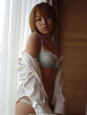 青と黄色のレースのブラジャーと白いオフショルダー シャツを着た、露出度の高い服装で窓...。