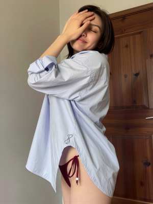 木製のドアの前に立って目を手で覆っている若い女性を横から撮影した写実的な写真。